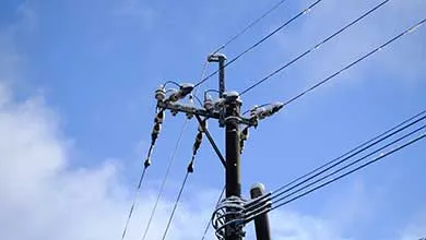 Snow-covered utility pole with power lines against a clear blue sky.
