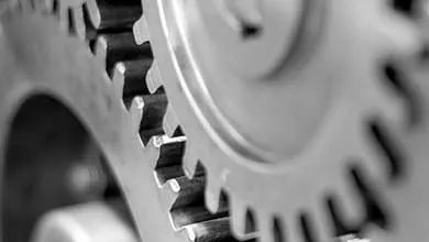 Close-up black-and-white image of two interlocking metal gears.