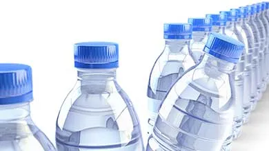 Close-up of several rows of clear plastic water bottles with blue caps on a white background.
