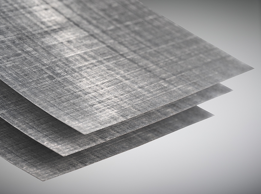 Close-up of three thin, gray composite sheets with a woven crosshatch texture, stacked.
